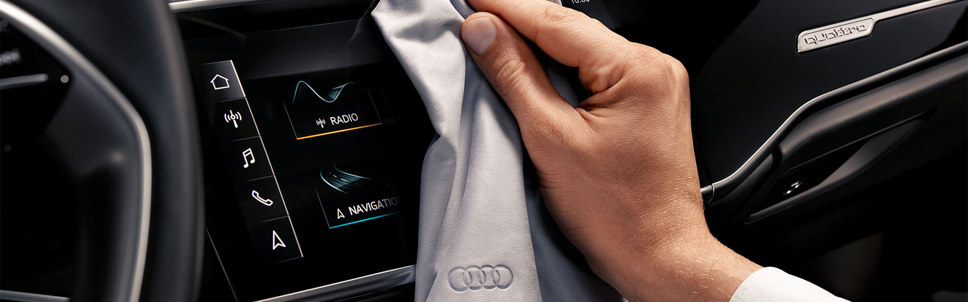 Stage Teaser Audi Original Pflegemittel - Hand mit Audi-Universal Pflegetuch wischt &uuml;ber Multimediadisplay